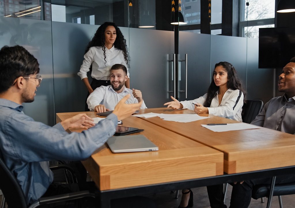 Multiracial business group in office meeting discuss project startup. Men and women coworkers partners team brainstorming ideas discussing marketing strategy at boardroom. Multiethnic company leaders. High quality photo